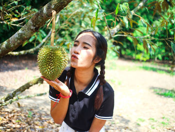 Young woman holding fruit growing on tree