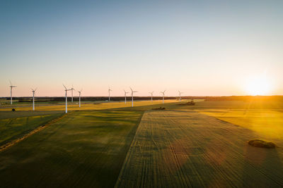 Drone view of windmills on grassy land against clear sky