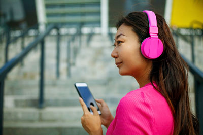 Asian girl in pink headphone in city