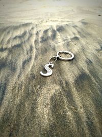 High angle view of key ring on sand at beach