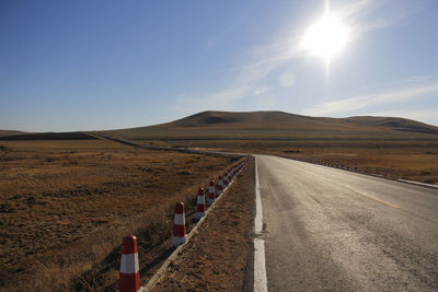 Road amidst field against sky