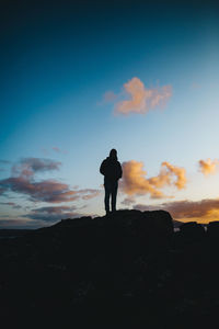 Rear view of silhouette man standing against sky during sunset