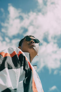 Low angle view of man wearing sunglasses standing against sky