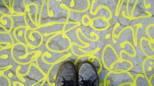 Low section of man wearing shoes standing on patterned street