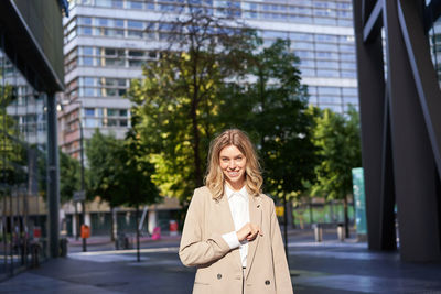 Portrait of young woman standing in city