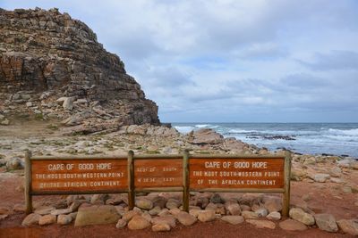 Information sign on rock by sea against sky