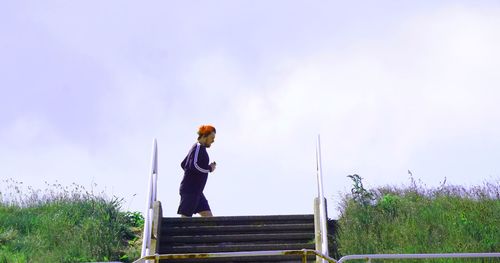 Side view of woman standing on field against sky