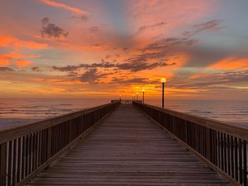 Pier over sea against sky during sunset