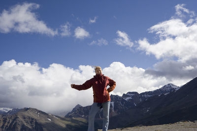 Low angle view of man standing on mountain against sky