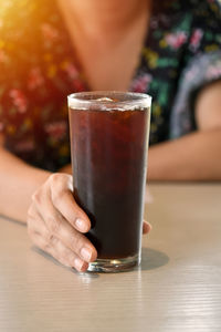 Close-up of hand holding drink on table