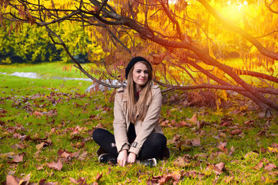 Portrait of young woman standing amidst tree during autumn