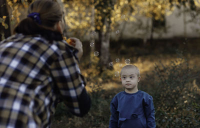Little boy with downs syndrome walks in the park with his mother, soap bubbles