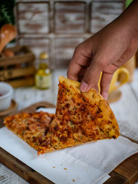 Close-up of hand holding pizza on table