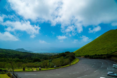 Road amidst green landscape against sky