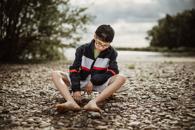 Full length of a boy sitting on pebbles