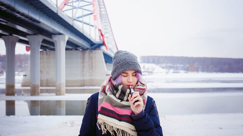 Full length of young woman photographing while standing on snow