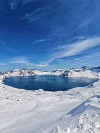 Scenic view of snowcapped mountains against blue sky