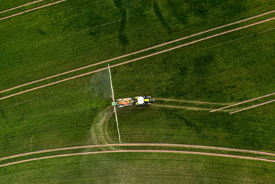 Top down view of the tractor spraying the chemicals on the large green field, agriculture concept