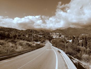 Empty road along landscape against sky