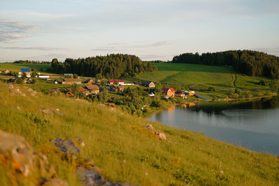 Scenic view of field by houses against sky