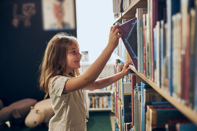 Schoolgirl choosing book in school library. back to school. learning and fun. primary education