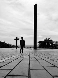 Rear view of man standing on footpath against sky