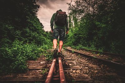 Rear view of man walking on railroad track