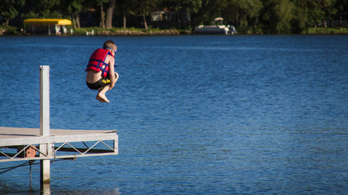 Boy jumping on lake during sunny day