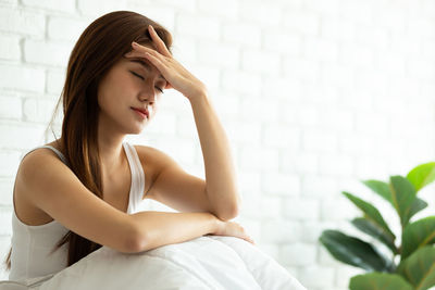 Young woman looking away while sitting on floor