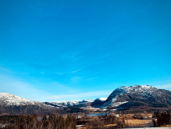 Scenic view of snowcapped mountains against blue sky