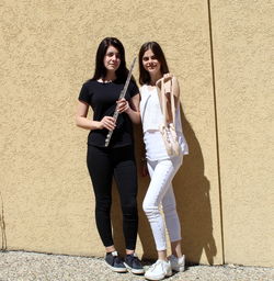 Portrait of smiling girls standing against wall outdoors