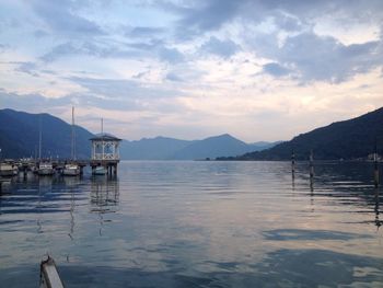 Gazebo on lake by mountains against sky