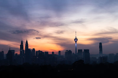 Menara kuala lumpur tower in city at sunset