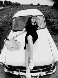 Young woman sitting on car