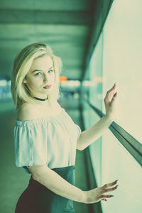 Portrait of young woman standing by window