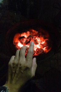 Close-up of hand by burning charcoal