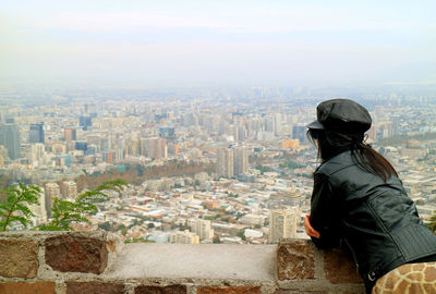 Side view of woman wearing leather jacket looking at cityscape
