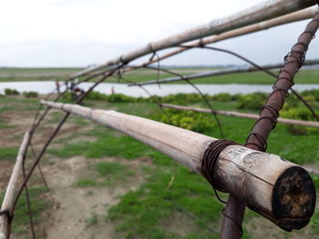 Close-up of rusty metal fence on field against sky