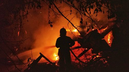 Silhouette firefighter against fire at night