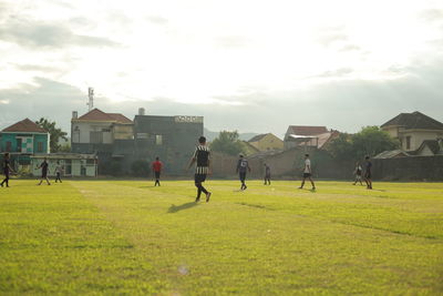 People playing on field against buildings