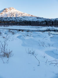 Snow covered landscape against clear blue sky