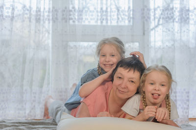Portrait of cute girls with grandmother lying on bed at home