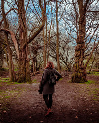 Rear view of woman photographing in forest