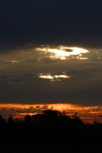 Silhouette landscape against dramatic sky during sunset