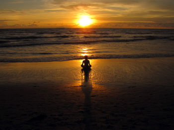 Silhouette person on beach against sky during sunset