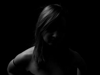 Portrait of young woman against black background