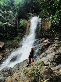 Rear view of man standing against waterfall