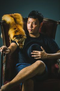 Young man with animal skin sitting on chair