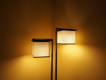 Illuminated electric lamps against wall at home