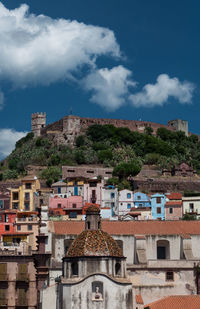 Buildings in town against cloudy sky